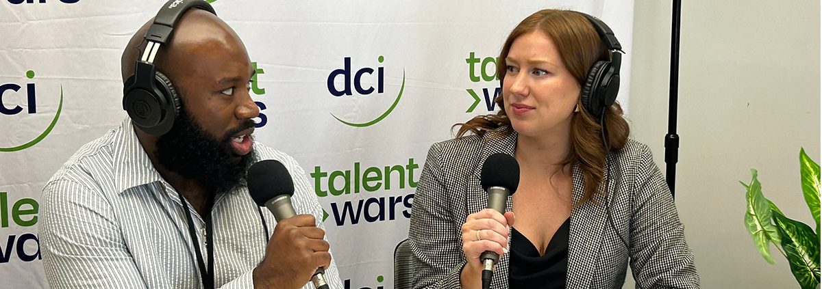 Two people sitting at a table holding microphones and talking