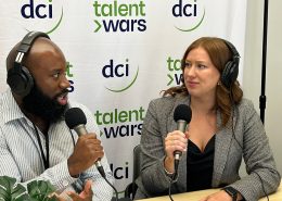 Two people sitting at a table holding microphones and talking