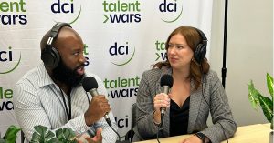 Two people sitting at a table holding microphones and talking